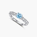 Geometric sterling silver ring with light blue moissanite center stone and square diamond accents on white background