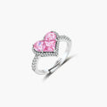 Heart-shaped ring with pink zirconia stones in white gold-plated setting, adjustable band on neutral background.